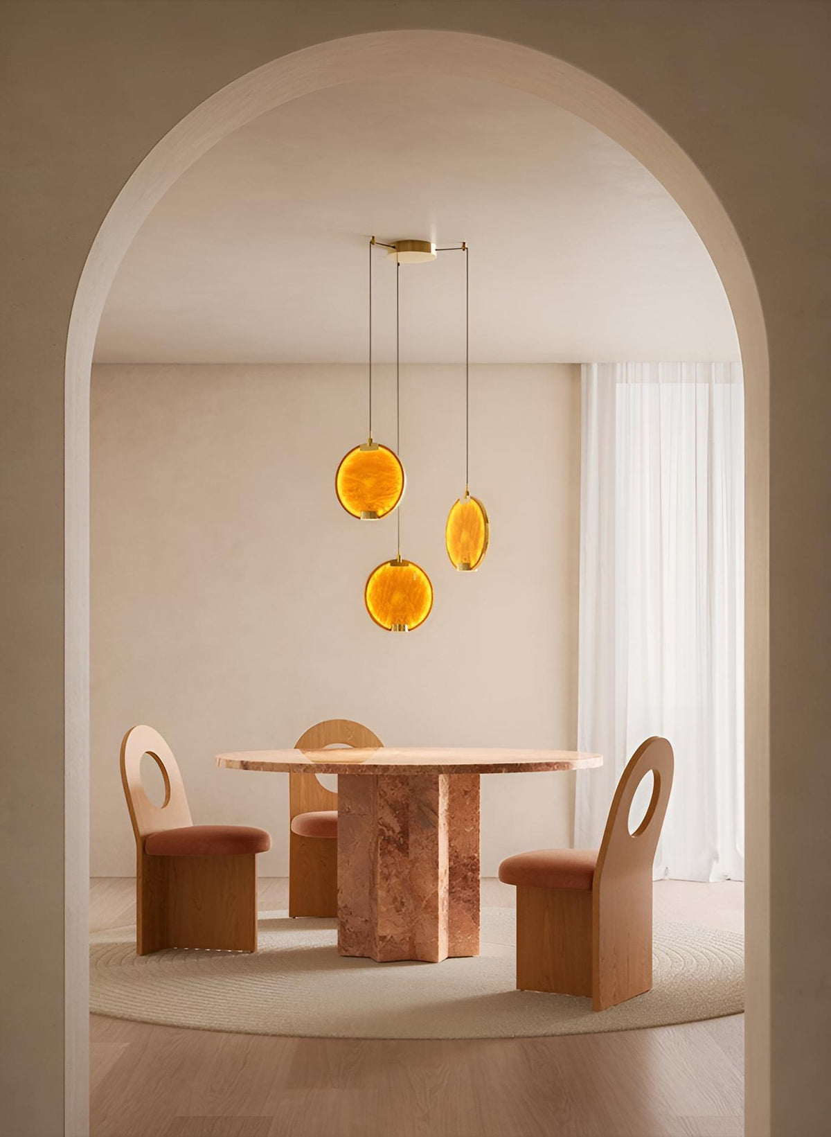 Lampadario Horo di Masiero con tre sospensioni circolari in vetro ambrato, installato sopra un tavolo da pranzo.