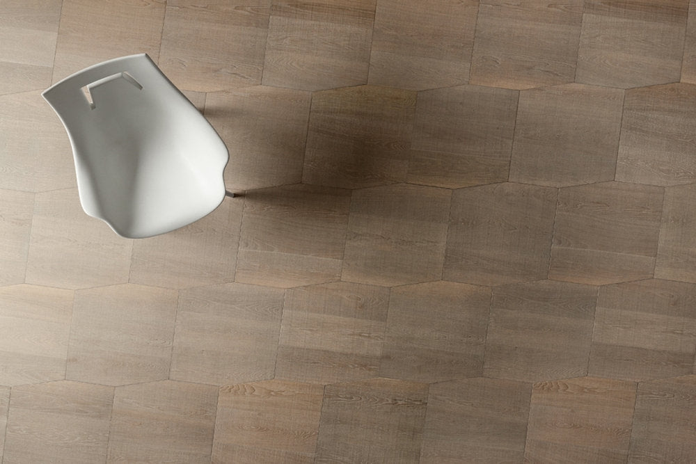 Parquet Yles Kytos in rovere finitura Ferrum con disegno modulare e sedia bianca.