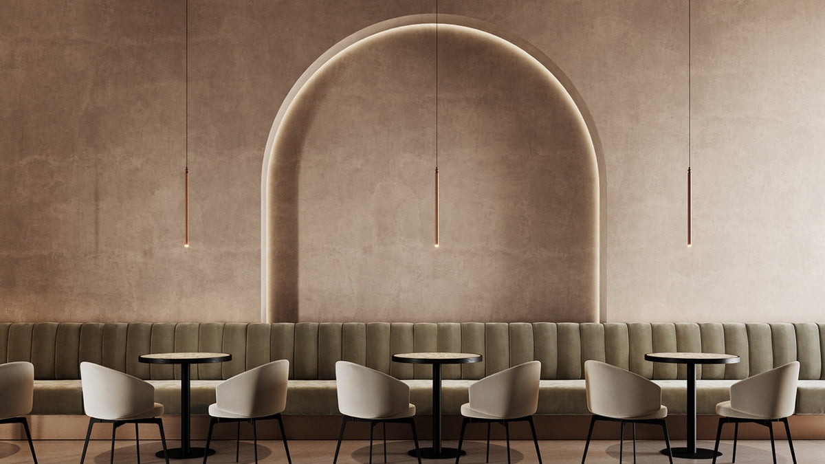 Tre lampade a sospensione LED Serica di Masiero in finitura rame, sopra i tavoli di un ristorante contemporaneo.