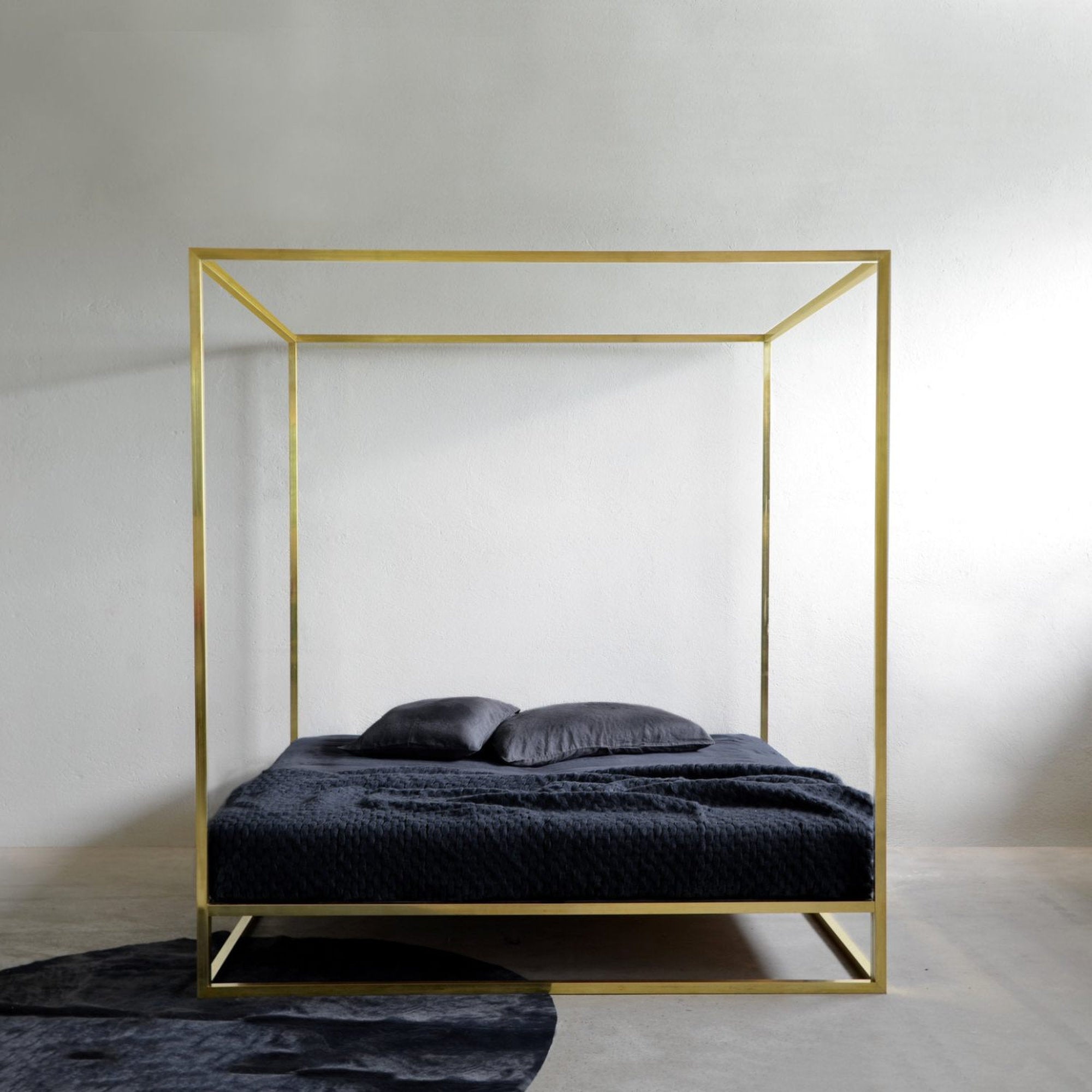 Letto minimal a baldacchino in ottone Asha di xam in ambiente con pavimento in resina