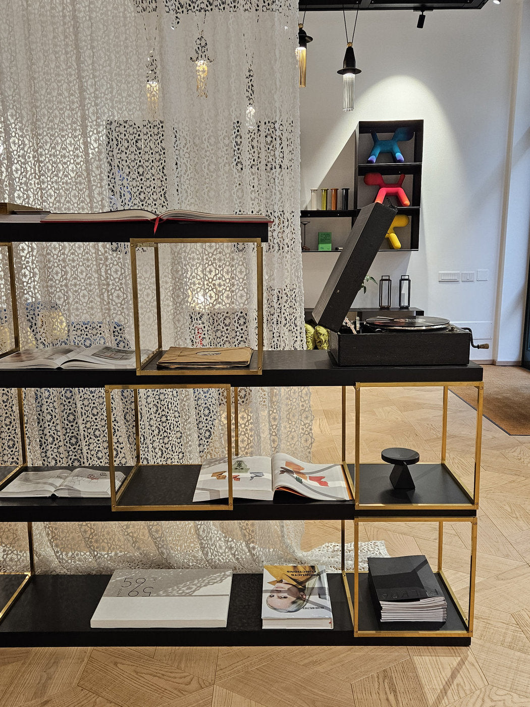 Libreria componibile Xam con cubi in ottone lucido con mensole nere allestimento showroom design Milano