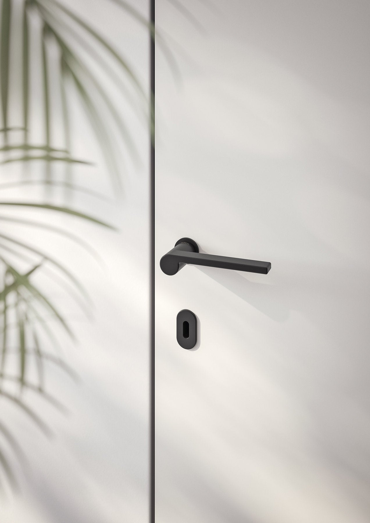 Maniglia Ento Lev nera opaca su porta bianca, dettaglio con rosetta e bocchetta