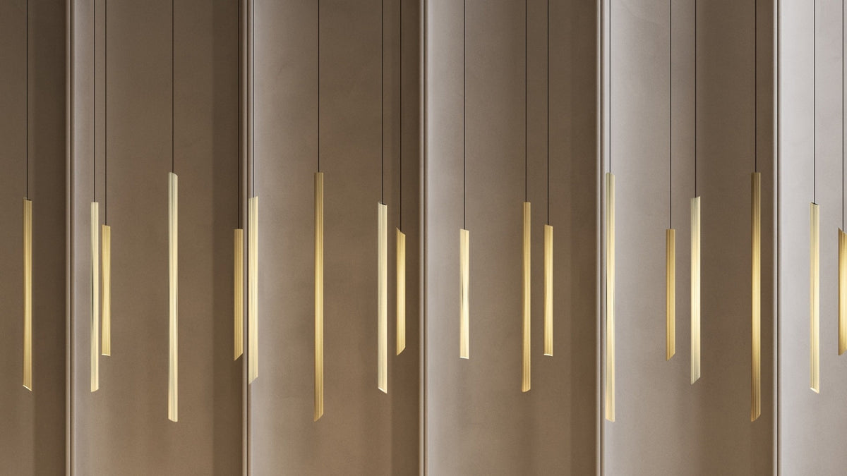 Dettaglio della sospensione Na-ar Cluster 28 Masiero con elementi cilindrici in ottone rigato e luce LED calda.