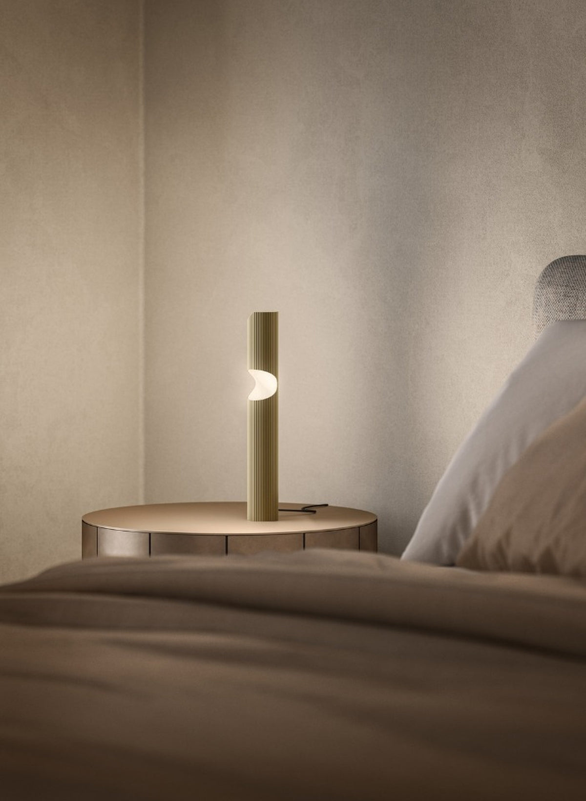 Lampada da comodino Na-ar TL di Masiero in ottone rigato, con luce LED calda e design cilindrico, accanto al letto.