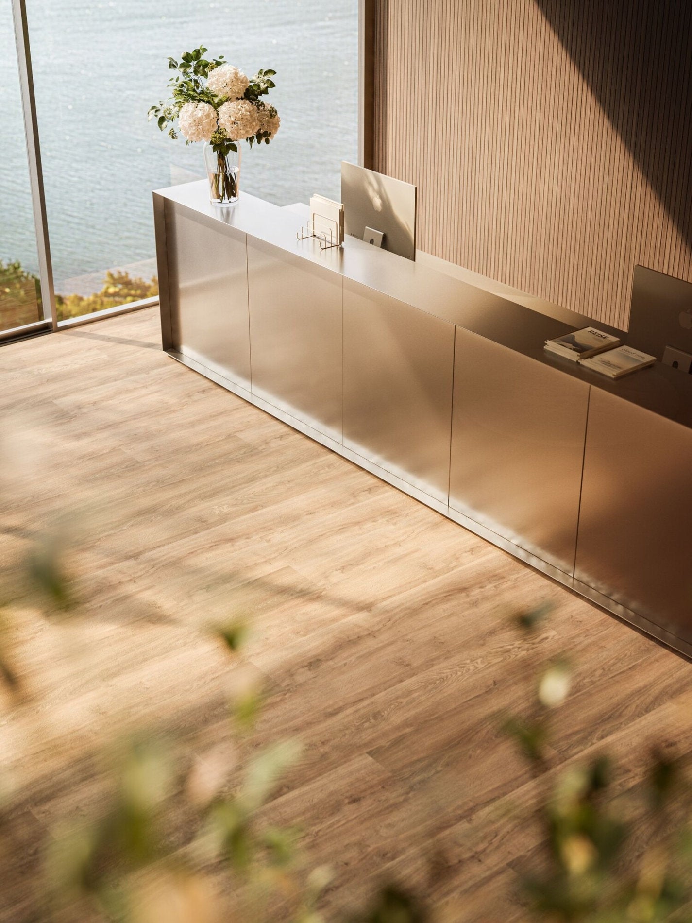 Reception con vista panoramica e pavimento effetto legno Rovere Autentico Star KR, abbinato a bancone in metallo satinato