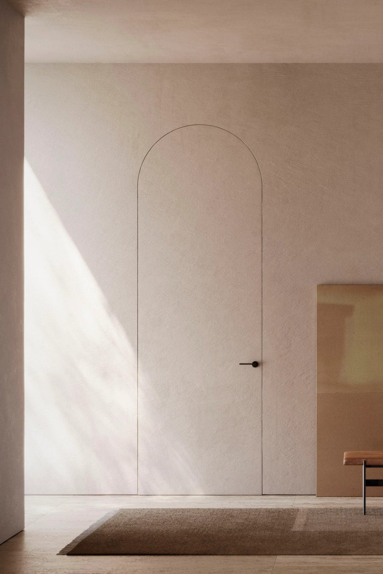 Porta rasomuro Viva con pannello ad arco integrato, maniglia nera e parete tono cipria.