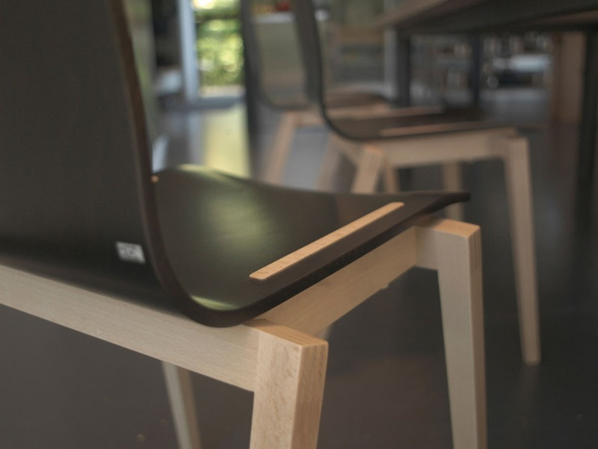 Dettaglio della sedia Stockholm TON con seduta scura e struttura in legno chiaro.