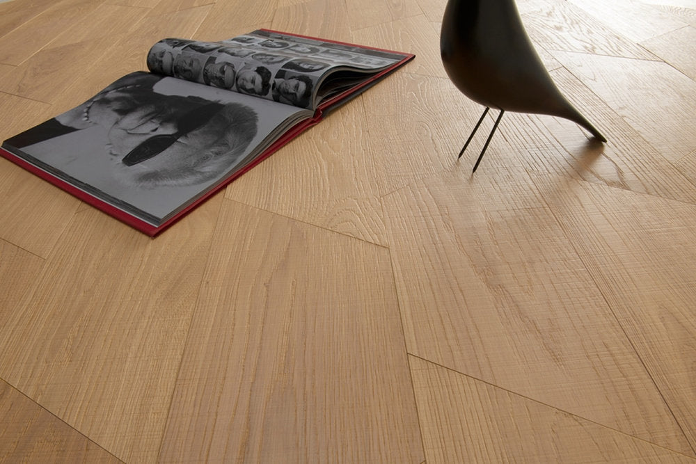 Dettaglio del pavimento Yles Tarsia in rovere finitura Neutra con texture spazzolata e libro aperto.