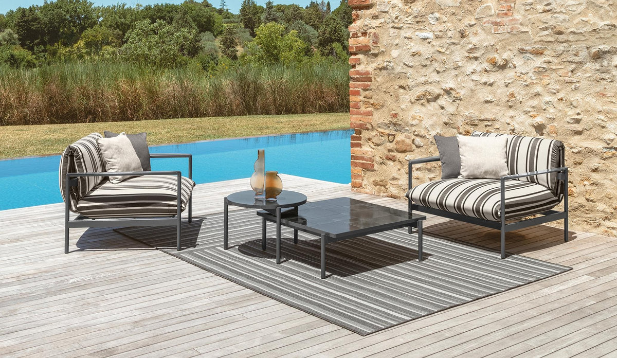 Zona lounge outdoor con tavolini Talenti Nalu in gres grafite, uno rotondo e uno rettangolare