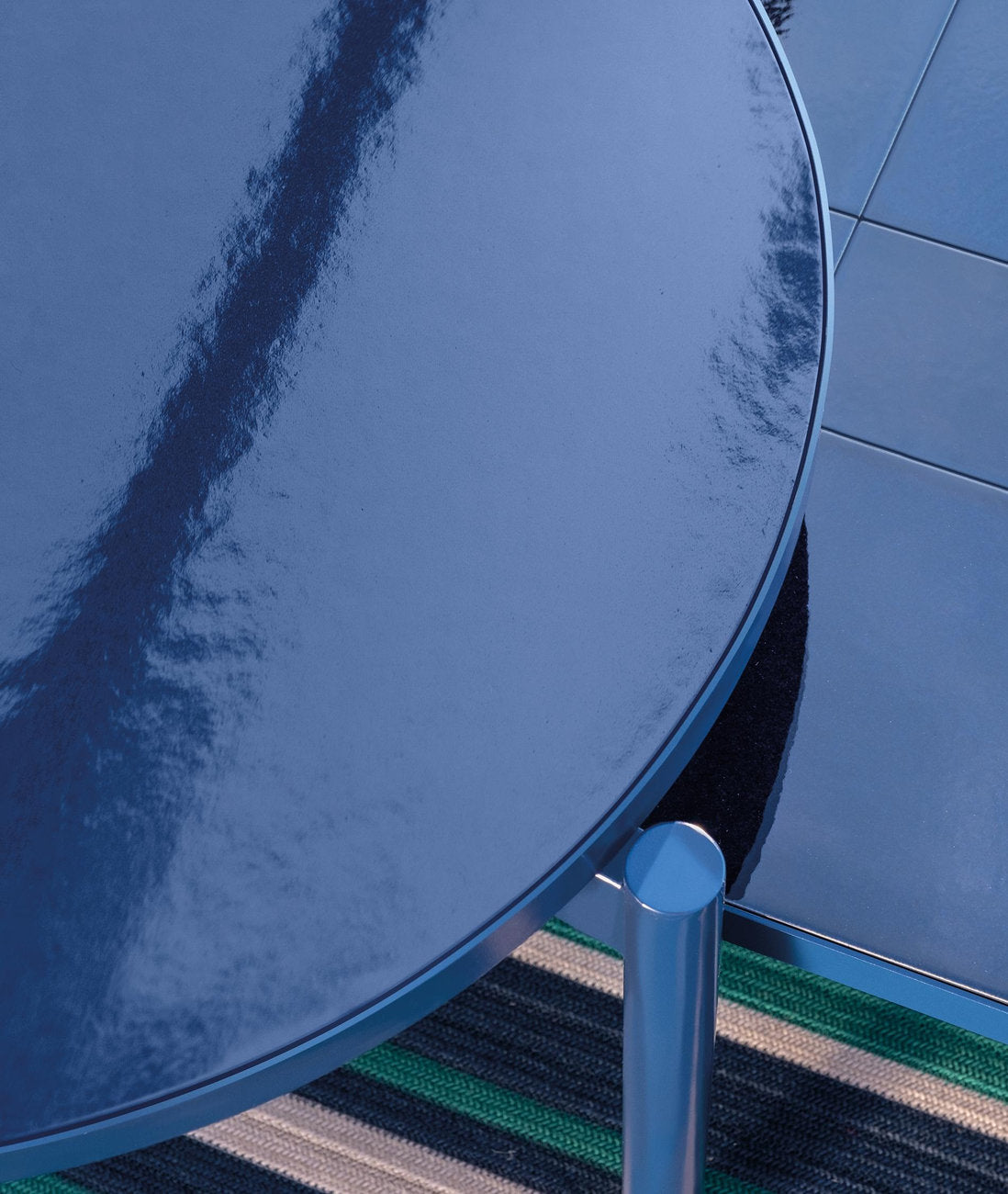 Dettaglio del tavolino da esterno rotondo Talenti Nalu in gres blu con struttura in alluminio