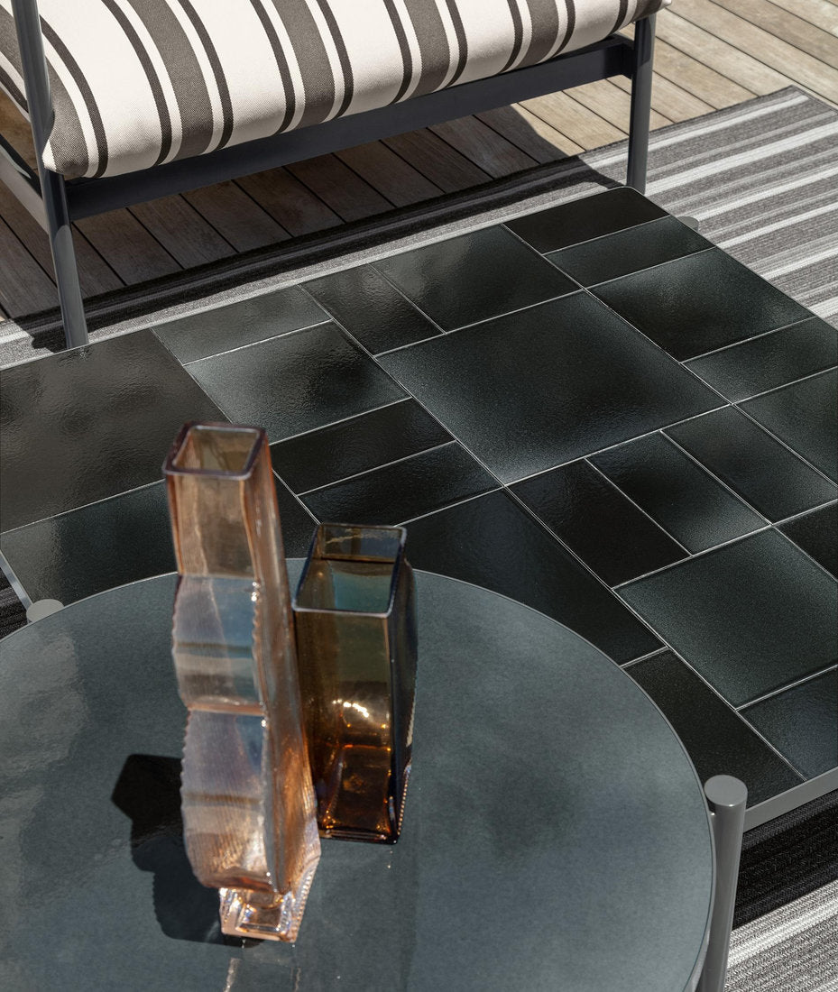 Dettaglio dei tavolini Talenti Nalu in grafite, rotondo e rettangolare, con piano in gres