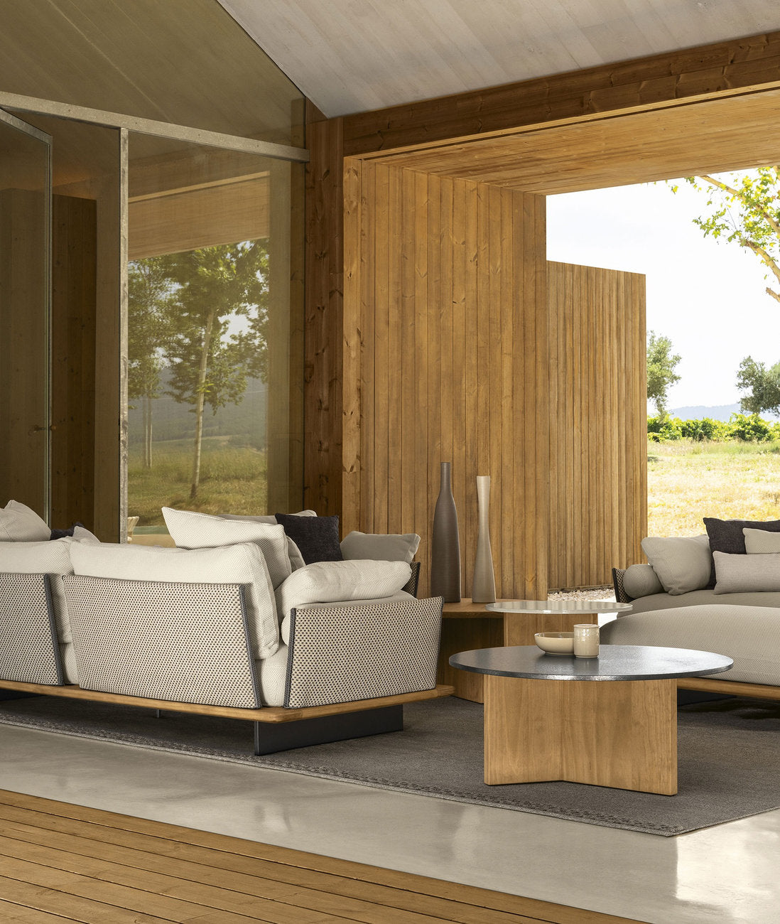 Divano outdoor Talenti Venice con tavolini bassi in legno e lava stone su patio coperto 
